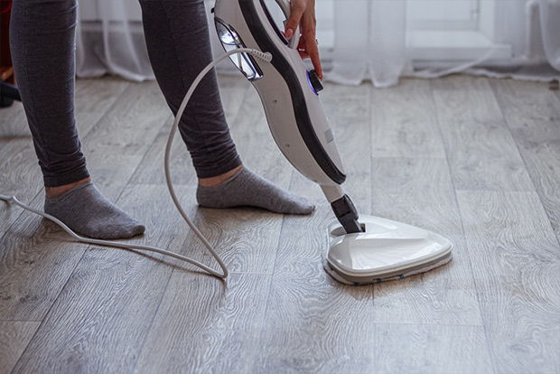 washes the floor with a modern steam cleaner