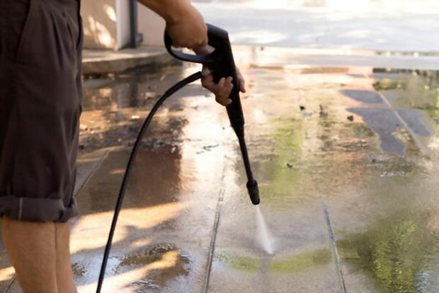 A close up picture showing someone cleaning his home using a pressure washer 