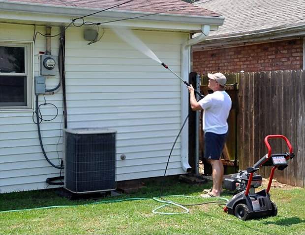 A picture showing a man using a pressure washer