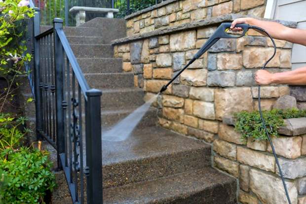 A close up picture showing someone cleaning his stairs using a pressure washer
