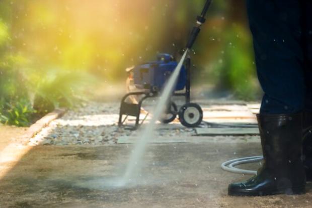 A close up picture of someone cleaning his pathway using a pressure washer