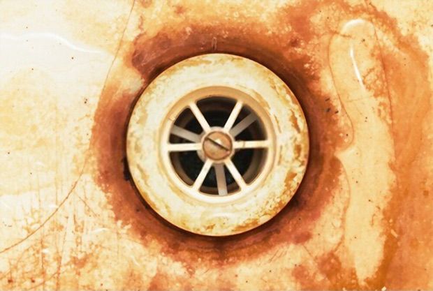 A closeup picture of a dirty and rusty bathroom sink drain