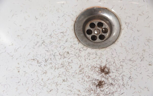 A sink drain with hair making it dirty