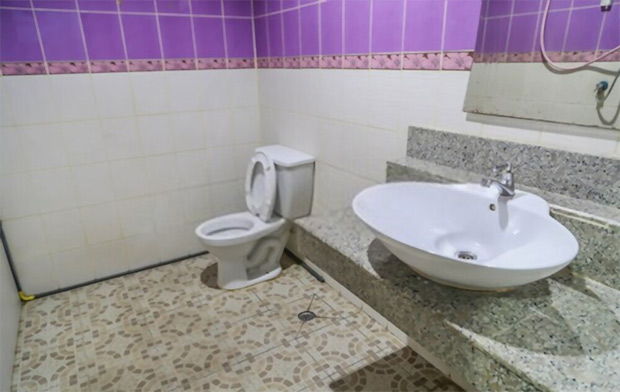 A toilet and a sink in a large spaced area