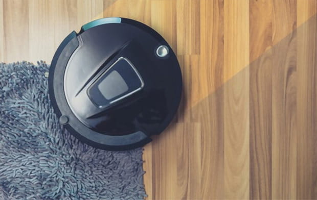 Robot vacuum cleaner cleaning on dusty wooden floor