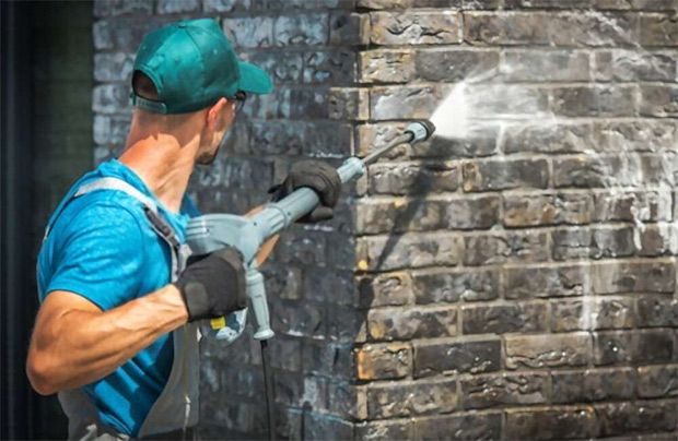 A cleaner wearing gloves while using a pressure washer