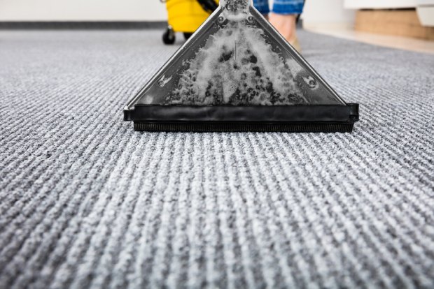Someone cleaning their carpet using a vacuum cleaner